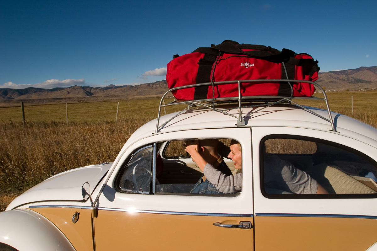 Eagle Creek campaign, a red Eagle Creek duffel strapped to the roof rack of a vintage Volkswagen Beetle with model Renae Vespremi inside