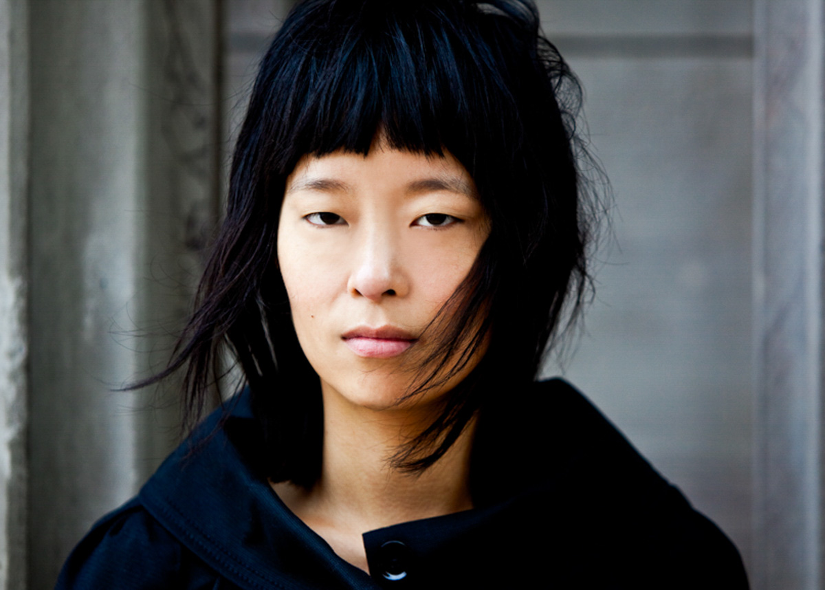 Close portrait of a model with dark bangs against a textured wall